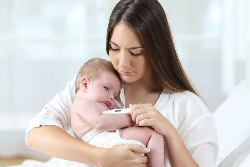 Mother using a thermometer with her baby