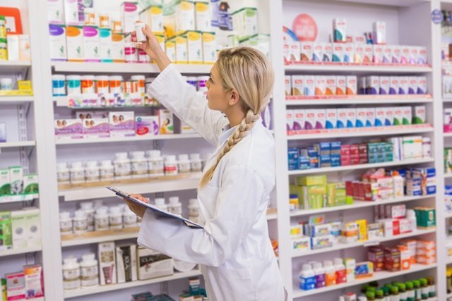 Junior pharmacist taking medicine from shelf