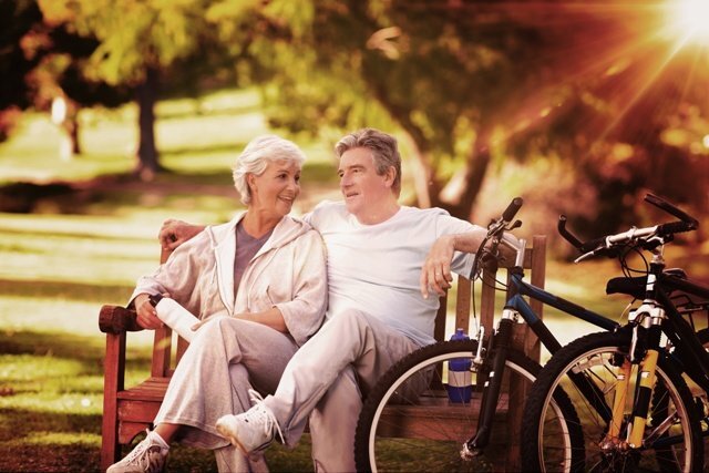 Composite image of elderly couple with their bikes