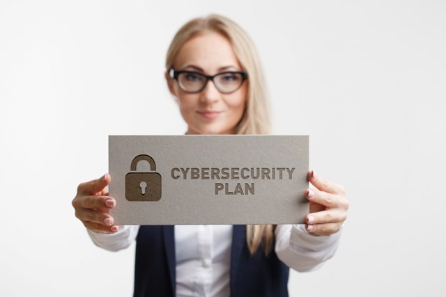 Business, Technology, Internet and network concept. Young girl holding a sign with an inscription CYBERSECURITY PLAN.