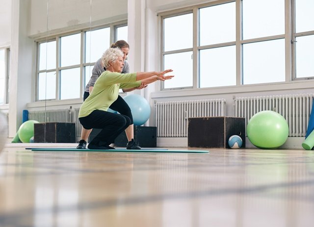 Senior woman doing exercise with her personal trainer