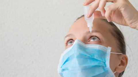 Mujer con mascarilla, usa lágrima artificial para el ojo seco
